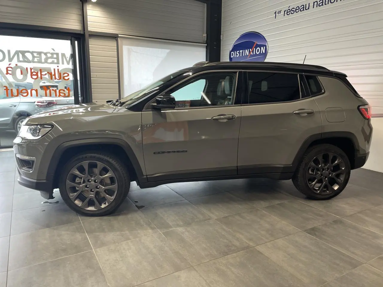 Jeep Compass gris foncé vu de profil côté gauche, avec jantes alliage foncé et vitres arrière surteintées.