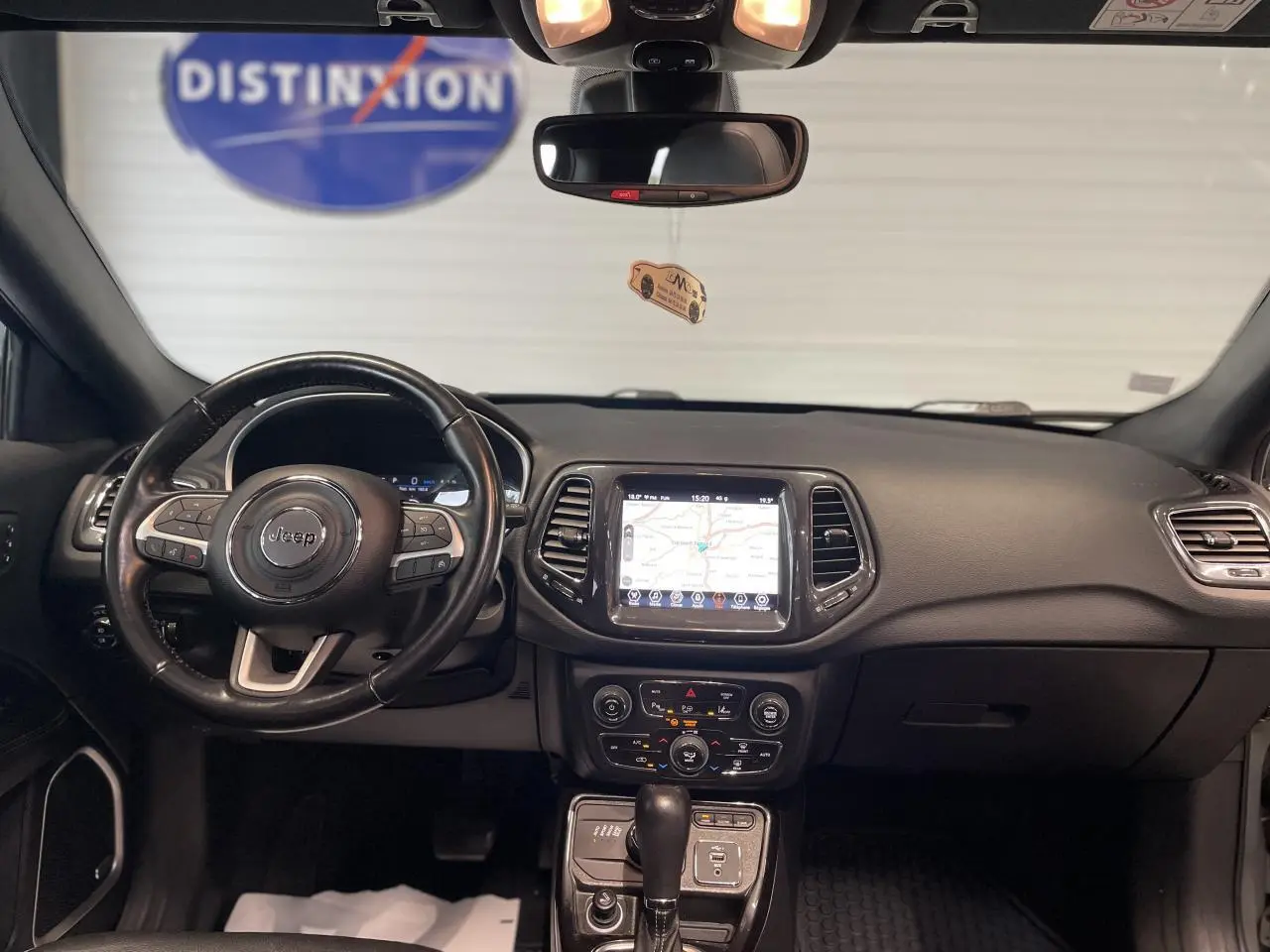 Vue intérieure frontale du tableau de bord noir du Jeep Compass 2021 avec écran tactile GPS et volant cuir.