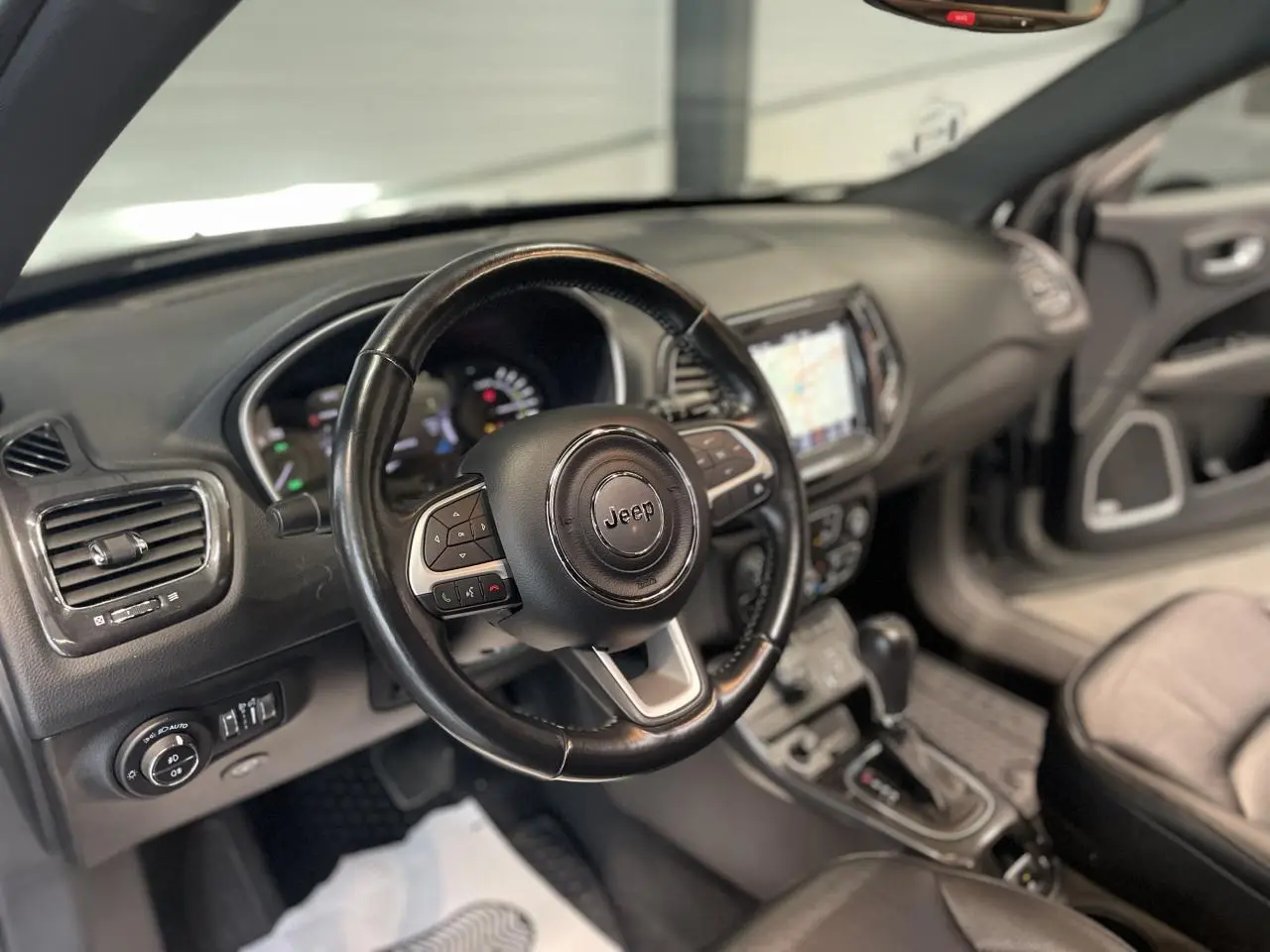 Intérieur du Jeep Compass 2021, vue côté conducteur sur le volant cuir et tableau de bord avec écran tactile.
