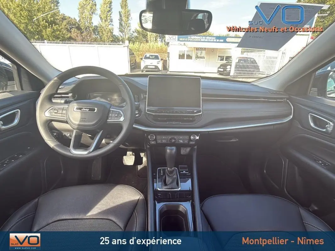 Vue intérieure frontale du Jeep Compass 2024 avec tableau de bord noir, écran tactile et volant multifonction.