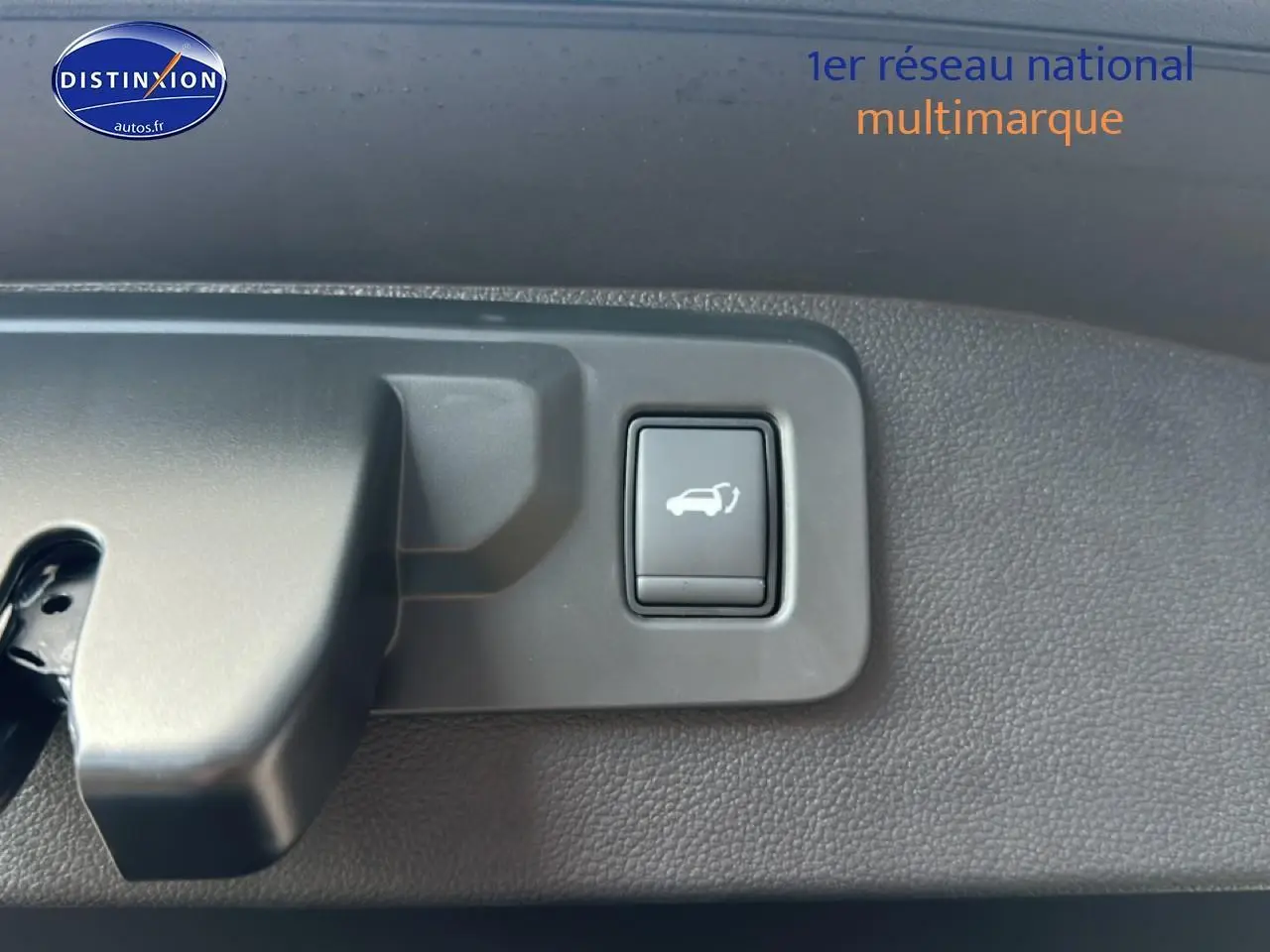 Bouton d'ouverture électrique du coffre sur panneau intérieur gris foncé du Renault Austral bleu.
