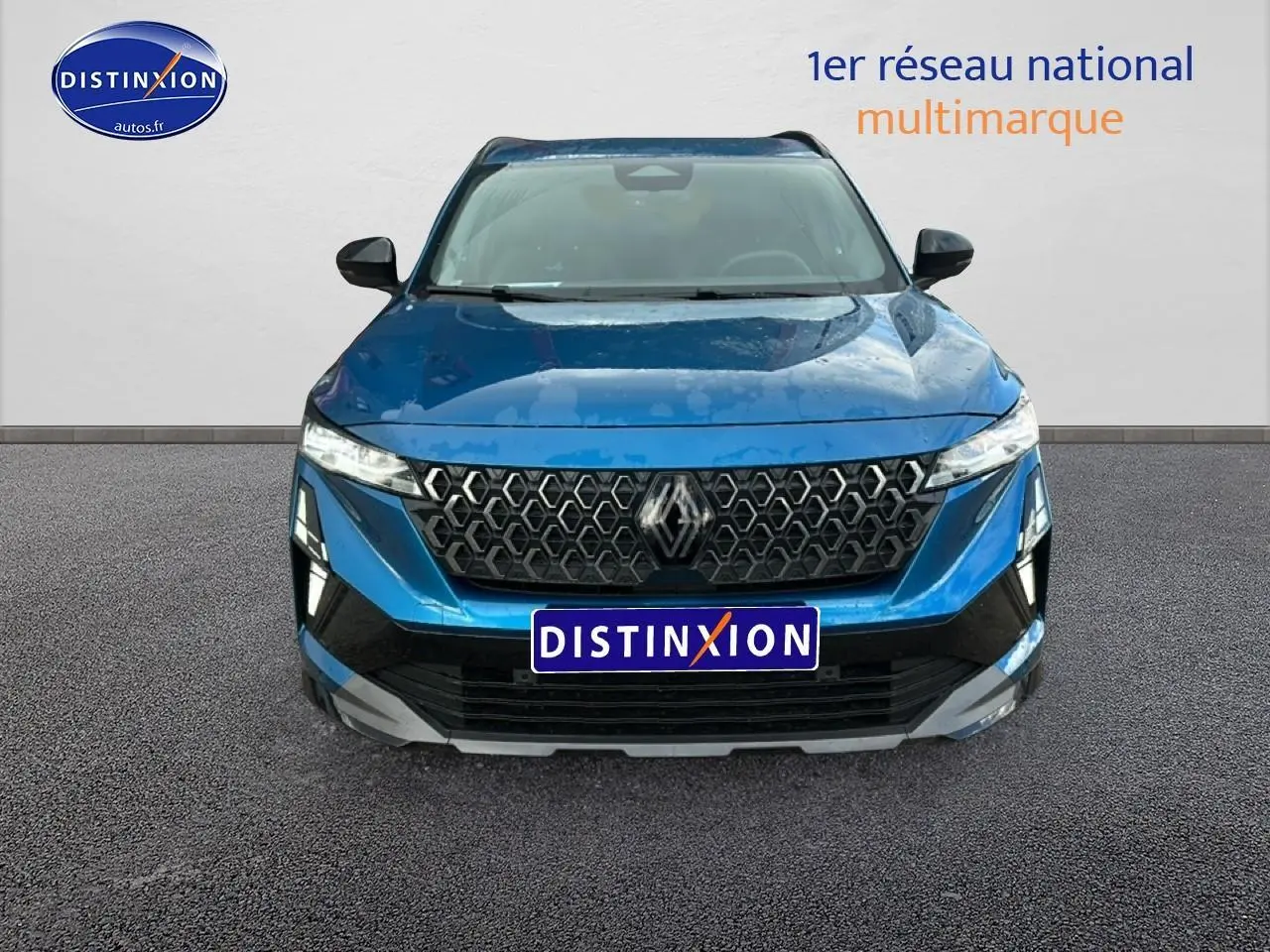 Vue frontale d'un Renault Austral bleu avec calandre noire à motifs hexagonaux et phares LED fins.