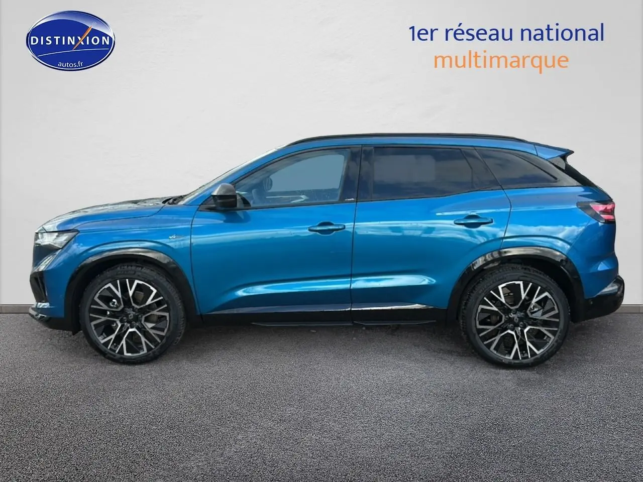 Profil gauche du Renault Austral bleu 2026 esprit alpine avec jantes alliage et barres de toit visibles.