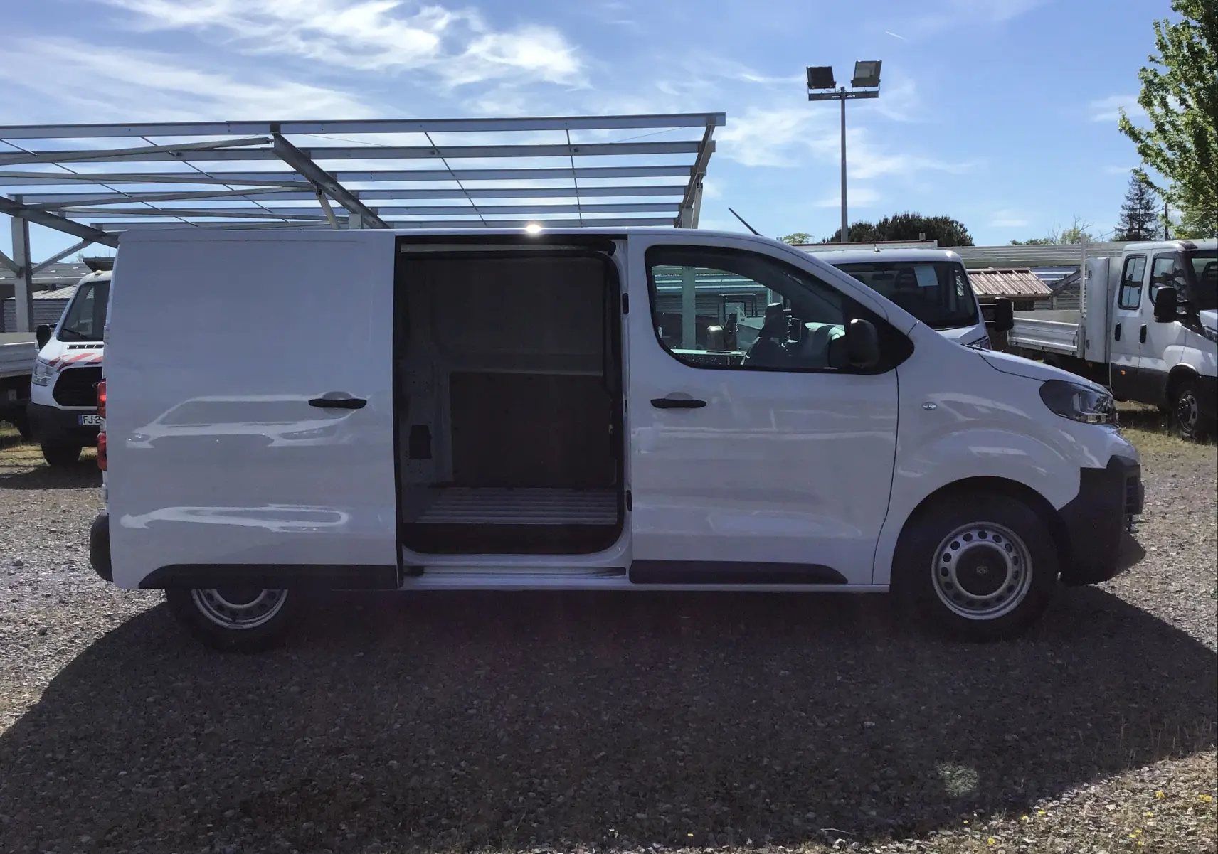 Vue de profil côté droit d'un Peugeot Expert Fourgon blanc 2025 avec porte coulissante ouverte montrant l'espace de chargement.