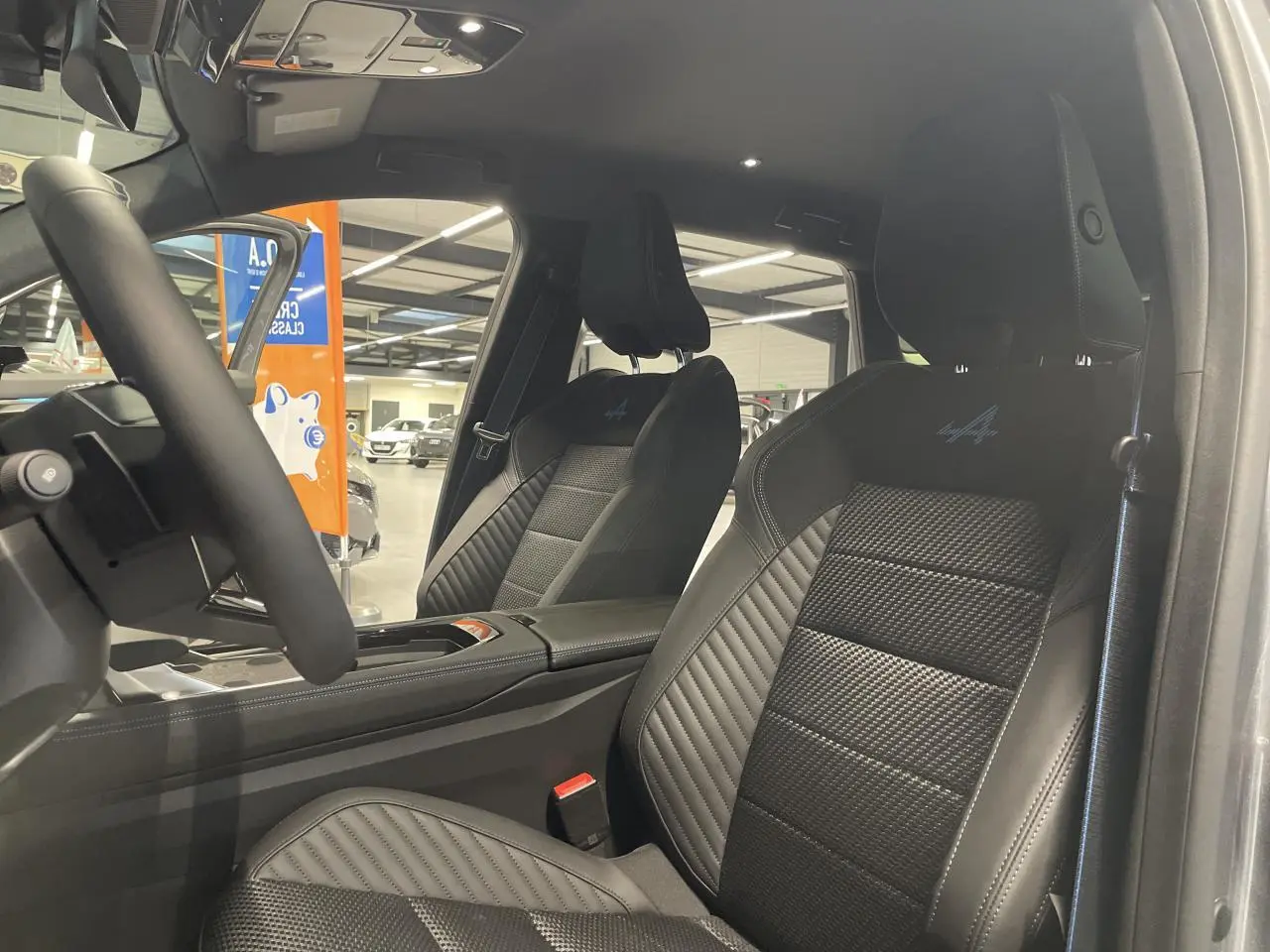 Vue intérieure côté conducteur du Renault Austral Esprit Alpine 2025, sièges noirs avec logo Alpine brodé bleu.