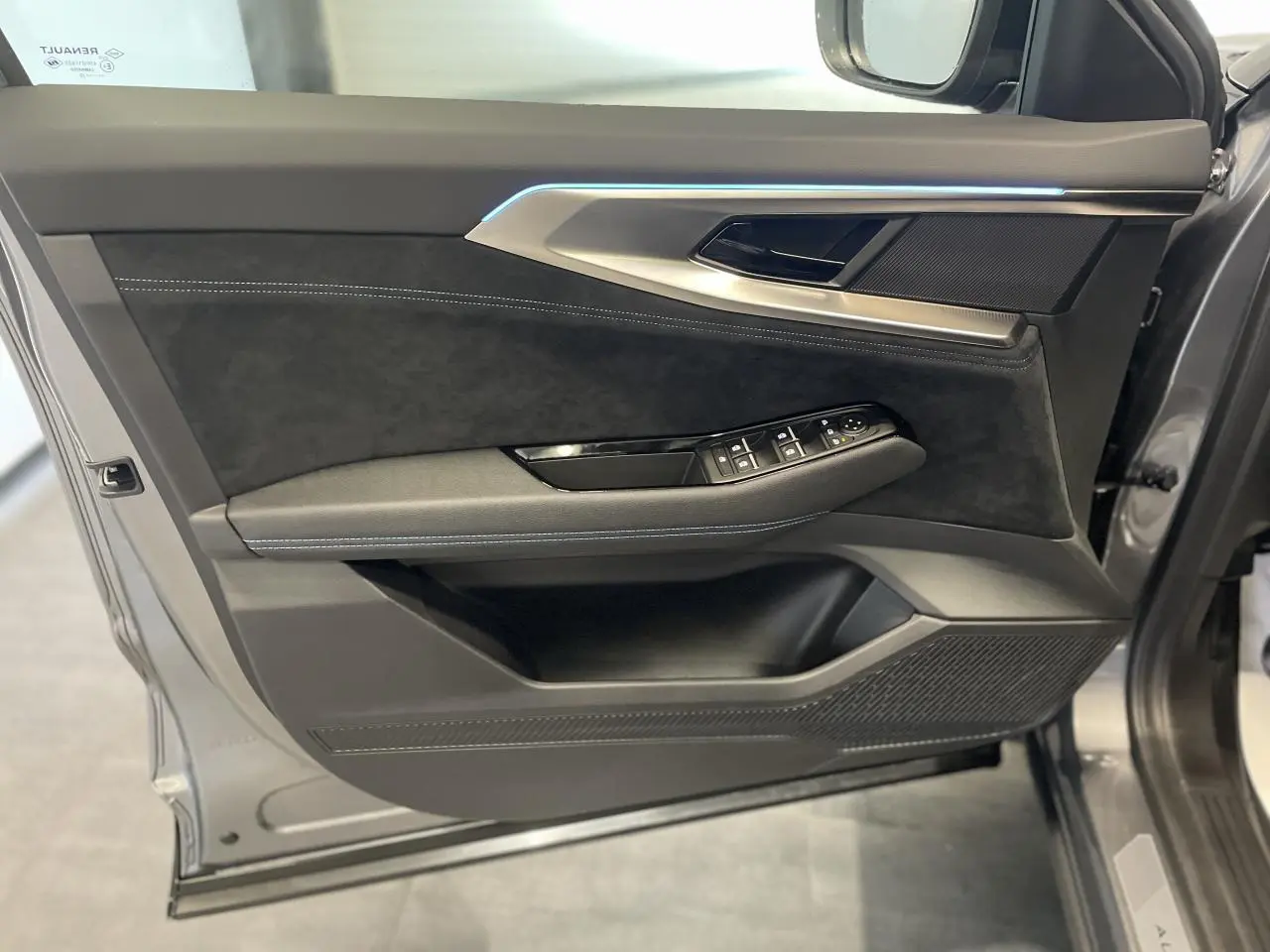 Intérieur côté gauche de la porte avant d'un Renault Austral 2025 gris métallisé avec garniture Alcantara noire et éclairage d'ambiance bleu.
