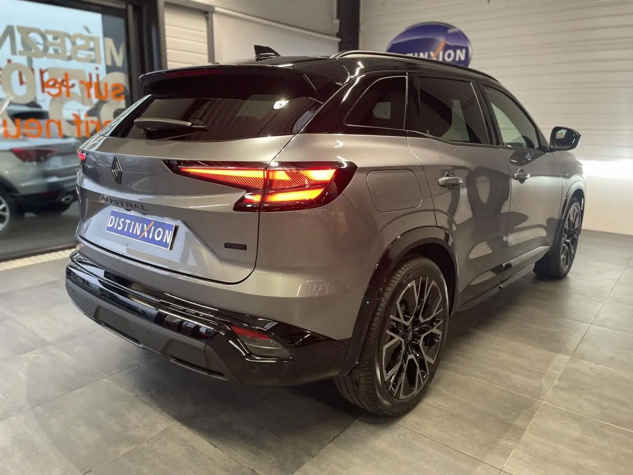 Vue 3/4 arrière droite du Renault Austral gris métallisé avec toit noir étoilé et jantes alliage noires.