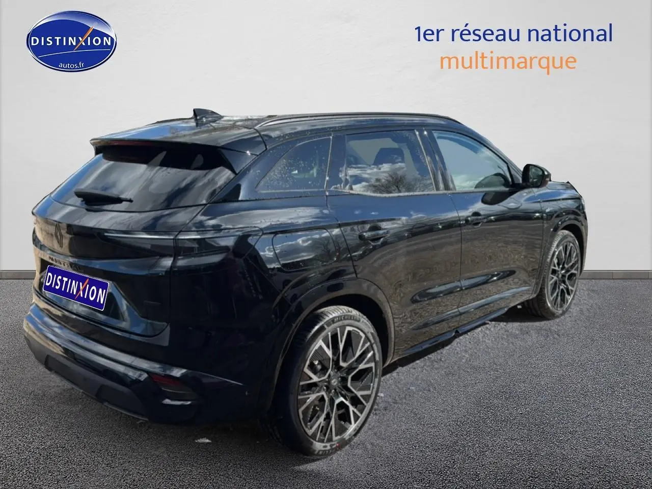 Vue 3/4 arrière droite d’un Renault Austral noir avec jantes alliage 20 pouces et barres de toit visibles.