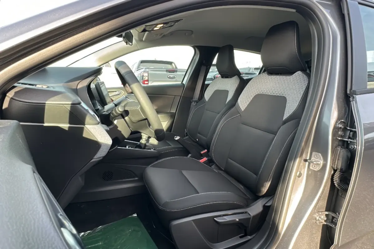 Vue intérieure côté conducteur de la Renault Clio gris schiste 2025, sièges avant bicolores noirs et gris.