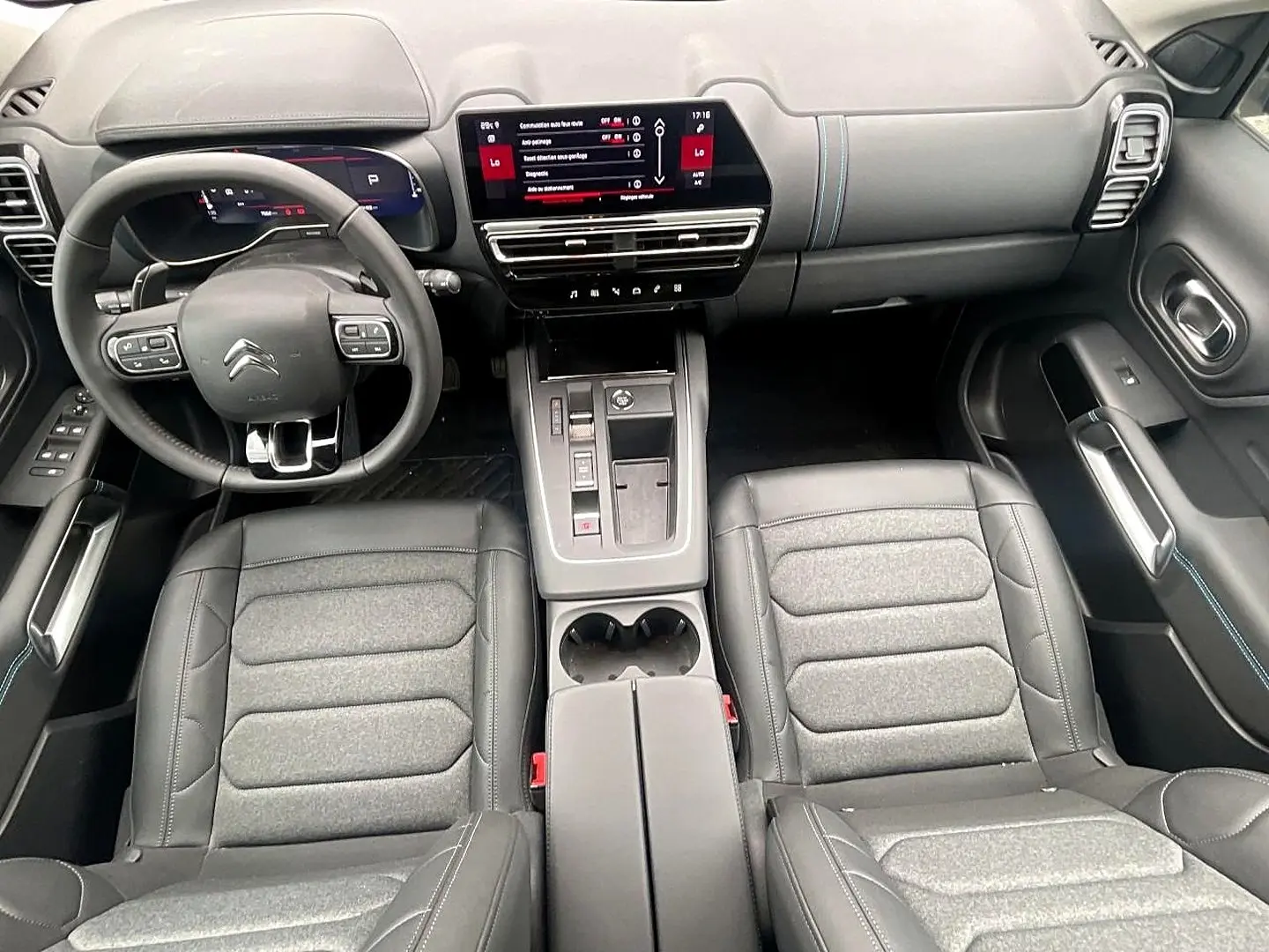Vue intérieure avant du Citroën C5 Aircross 2025 noir, avec tableau de bord numérique et sièges en cuir gris.