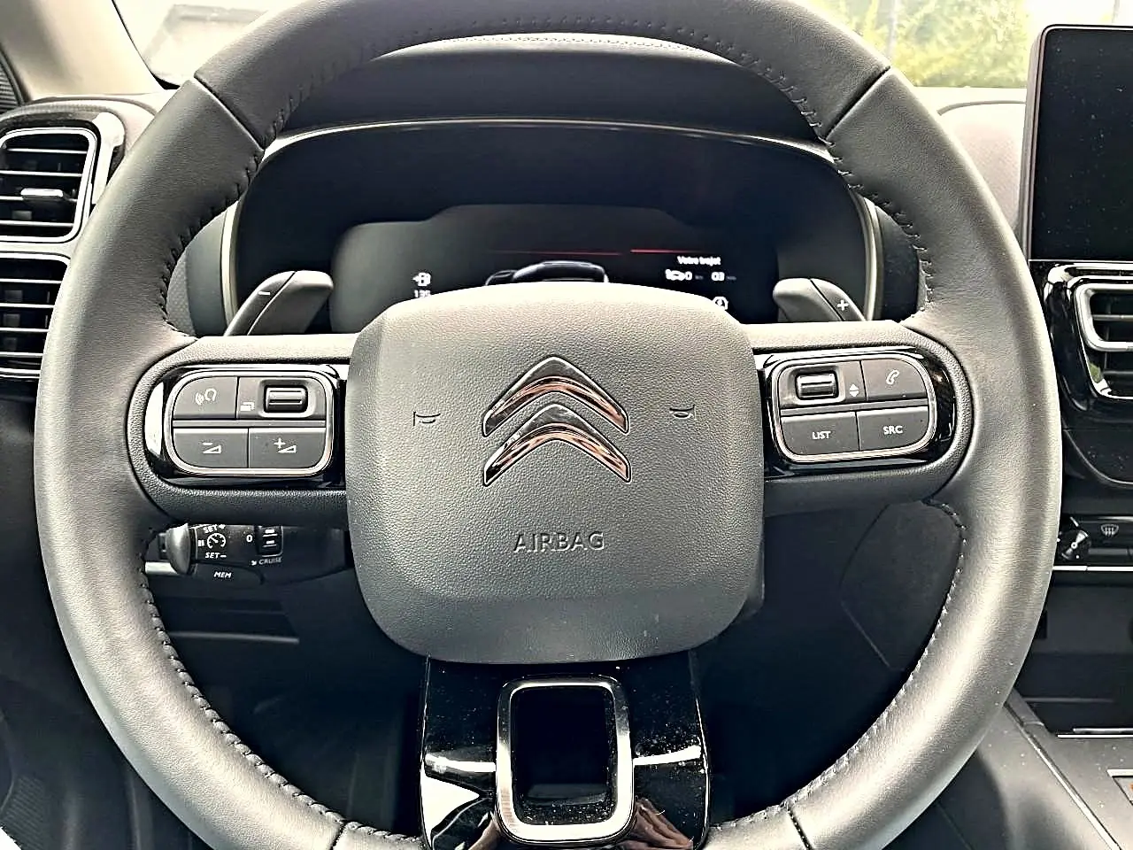 Vue rapprochée du volant noir multifonction du Citroën C5 Aircross avec commandes intégrées et logo chromé au centre.