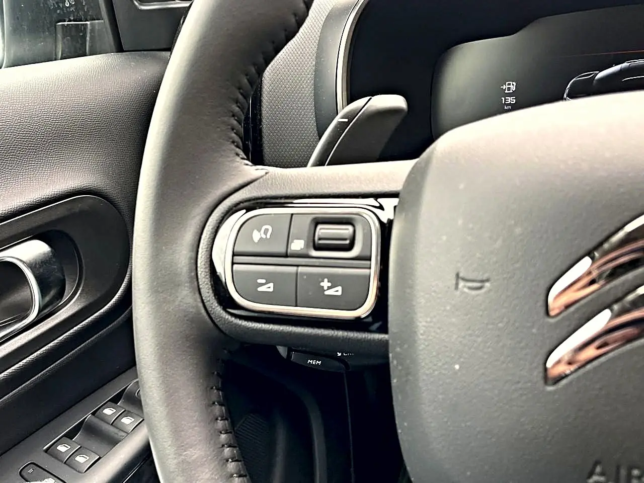 Gros plan sur le volant noir du Citroën C5 Aircross 2025 avec commandes multifonctions côté gauche et porte intérieure visible.
