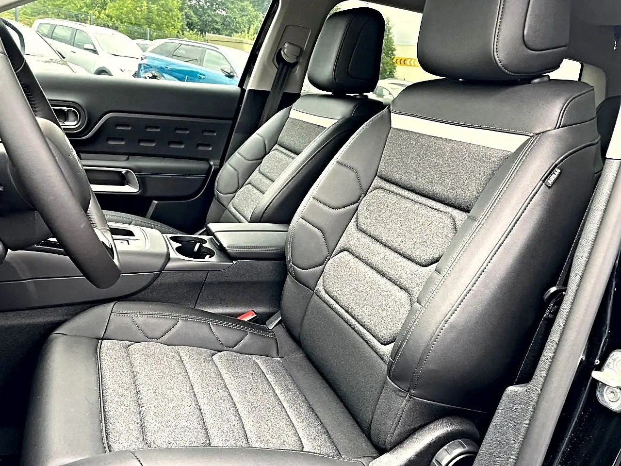 Vue intérieure côté avant droit du Citroën C5 Aircross 2025, sièges bi-matière gris et noir avec accoudoir central.