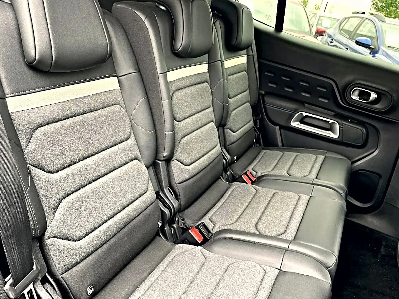 Vue latérale droite de la banquette arrière grise et noire du Citroën C5 Aircross avec appuie-têtes et ceintures visibles.