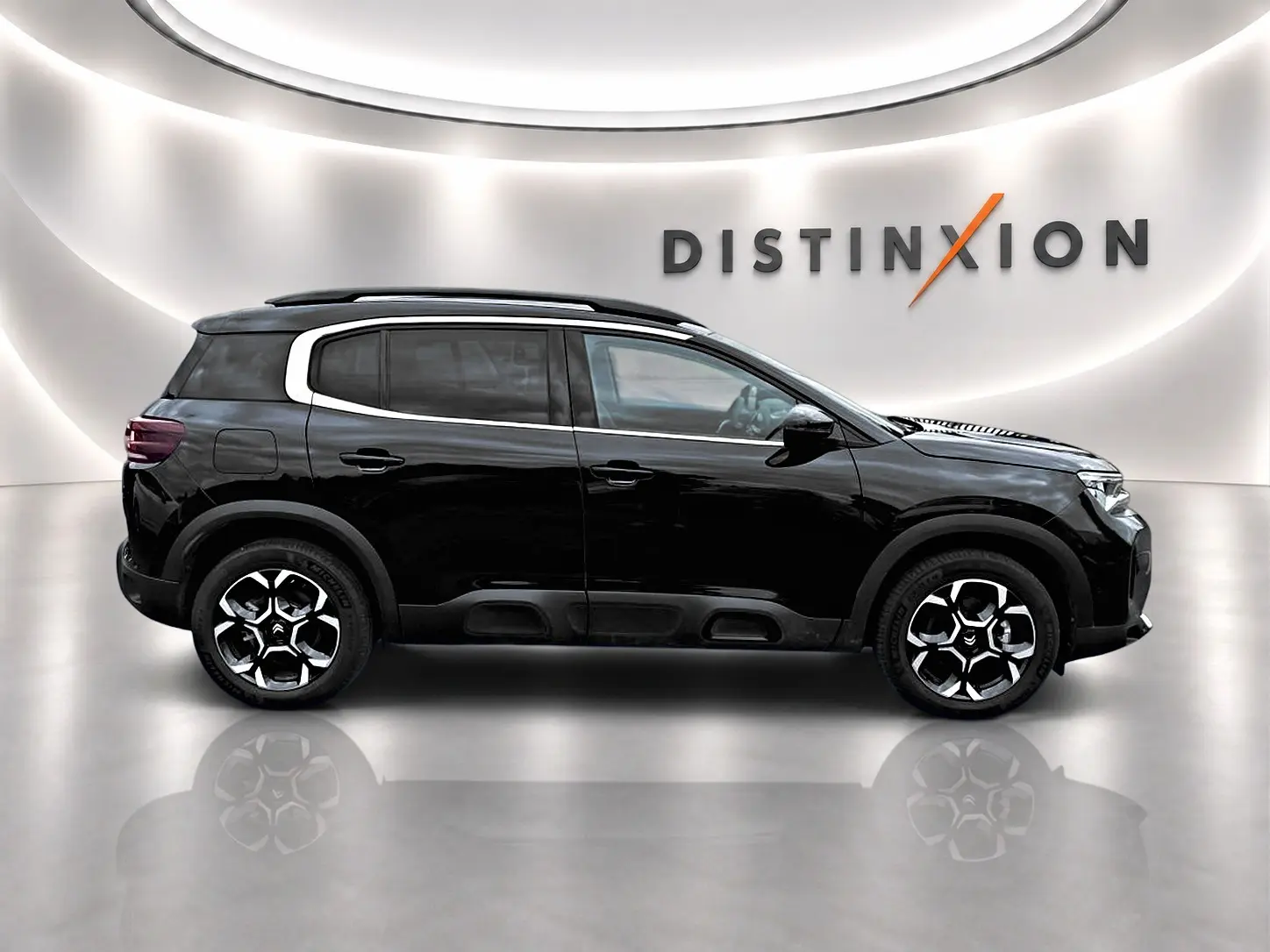 Profil droit du Citroën C5 Aircross noir 2025 avec jantes alu et toit noir dans un showroom lumineux.