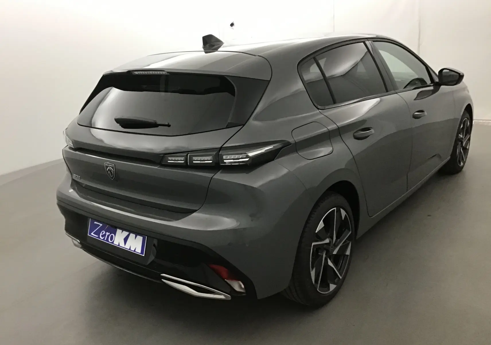 Vue 3/4 arrière droite d'une Peugeot 308 gris selenium avec feux LED et jantes alliage noires et argentées.