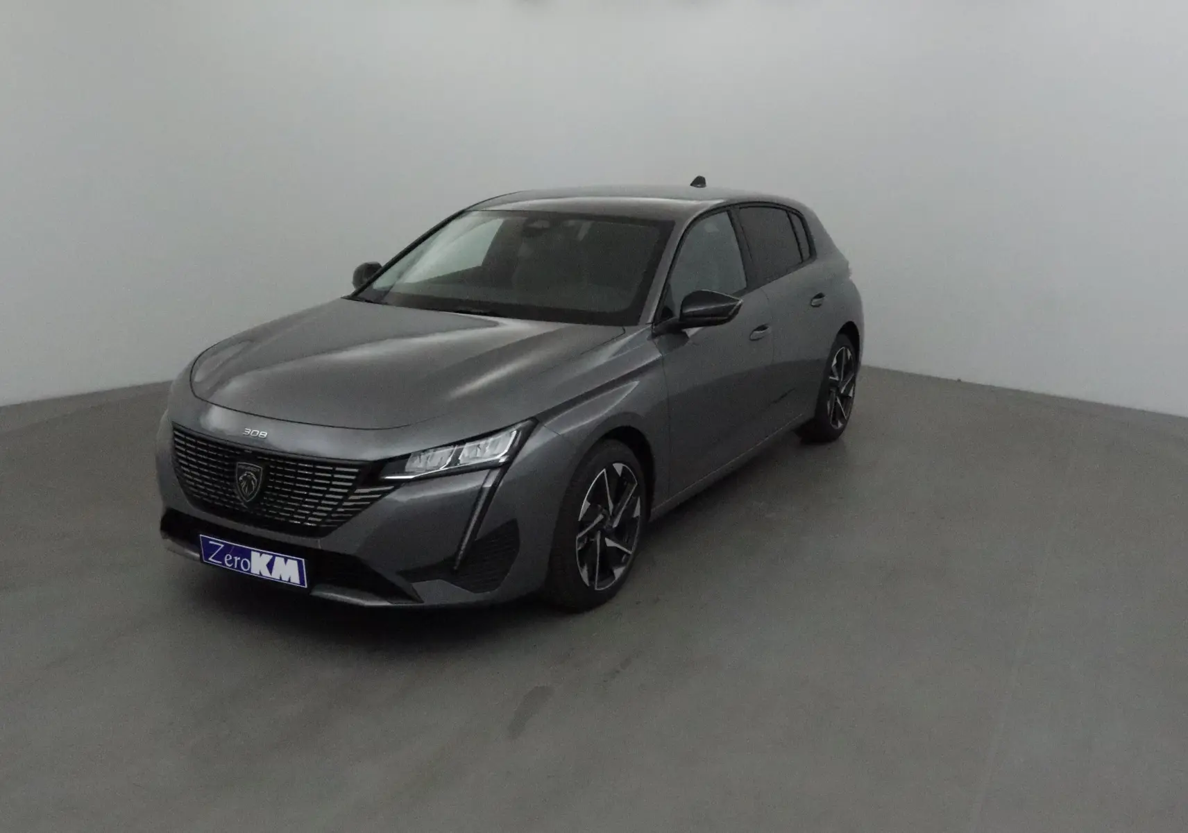 Peugeot 308 gris sélénium vue 3/4 avant droit dans un studio, avec calandre noire et jantes alliage.