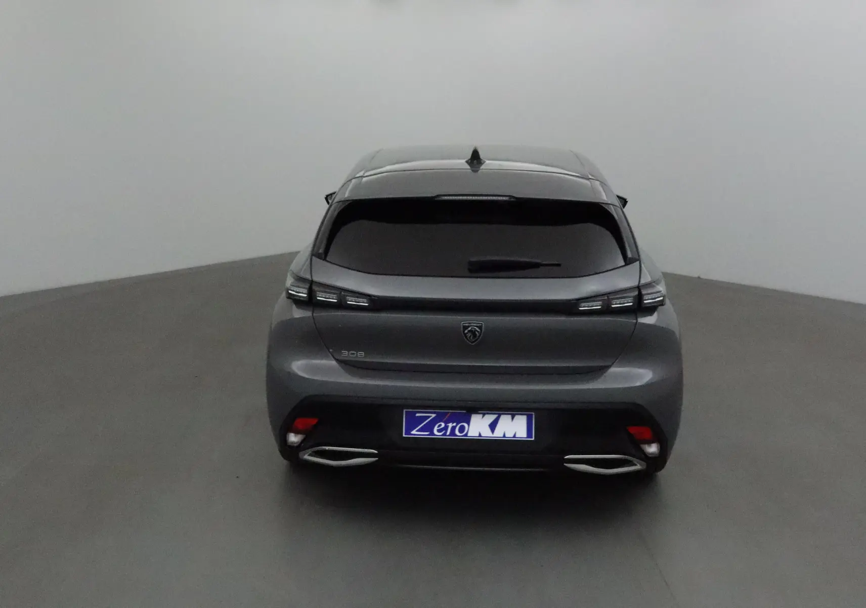 Vue arrière d'une Peugeot 308 gris selenium avec feux LED effilés et double sortie d'échappement chromée.