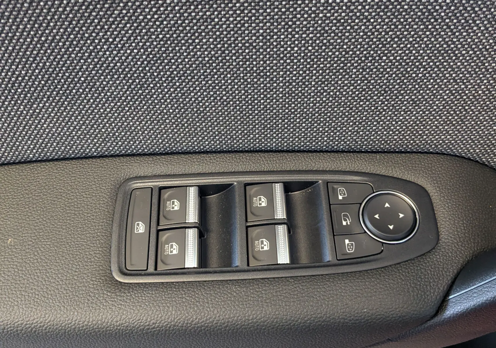 Panneau de commandes des vitres et rétroviseurs sur la porte côté conducteur d'un Renault Captur rouge flamme 2025.