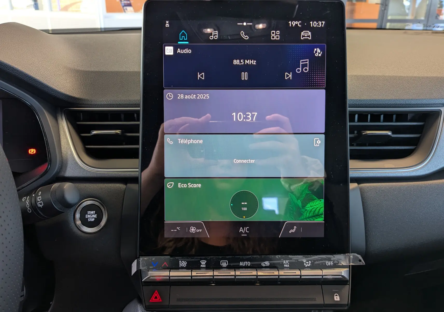 Écran tactile central du tableau de bord du Renault Captur 2025 avec commandes climatisation et bouton start/stop visible à gauche