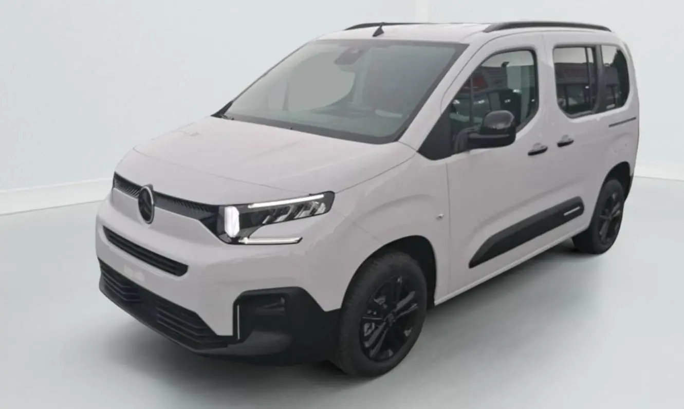 Citroën Berlingo blanc en 3/4 avant droit avec jantes noires et barres de toit visibles sur fond clair.