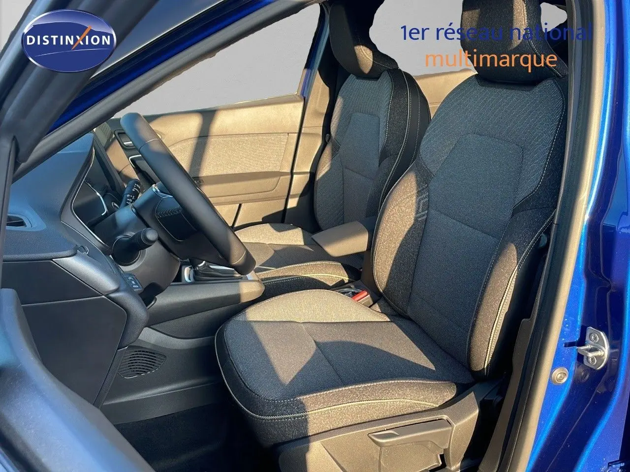 Intérieur avant droit du Renault Captur E-Tech hybride 2025 avec sièges tissu gris et portière bleu iron metal ouverte.