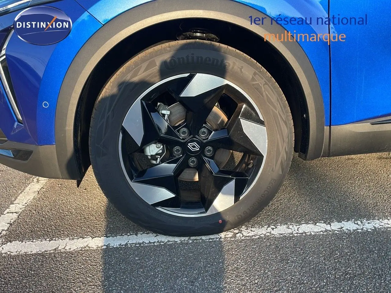 Gros plan sur la roue avant gauche du Renault Captur bleu Iron Metal avec jante noire et grise au design moderne.