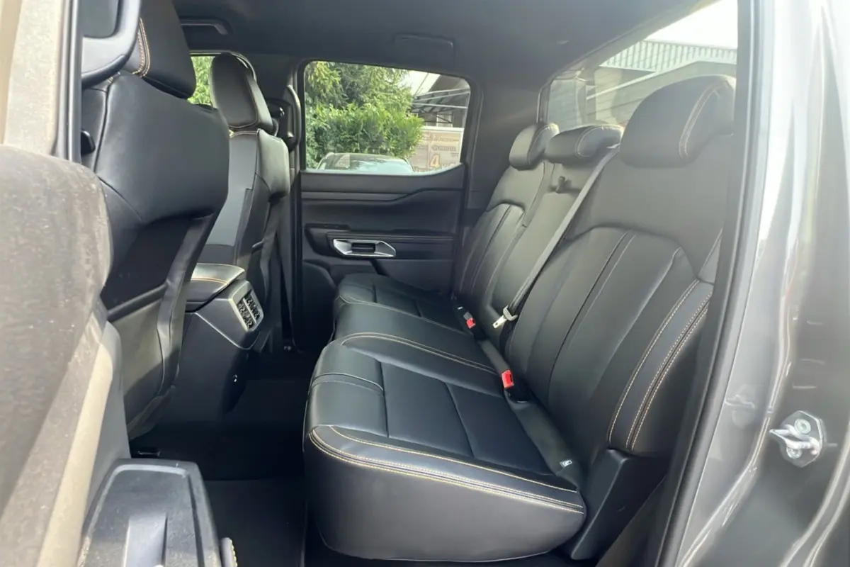 Vue intérieure arrière droite du Ford Ranger 2025 gris carbone, montrant les sièges en cuir noir avec surpiqûres contrastées.