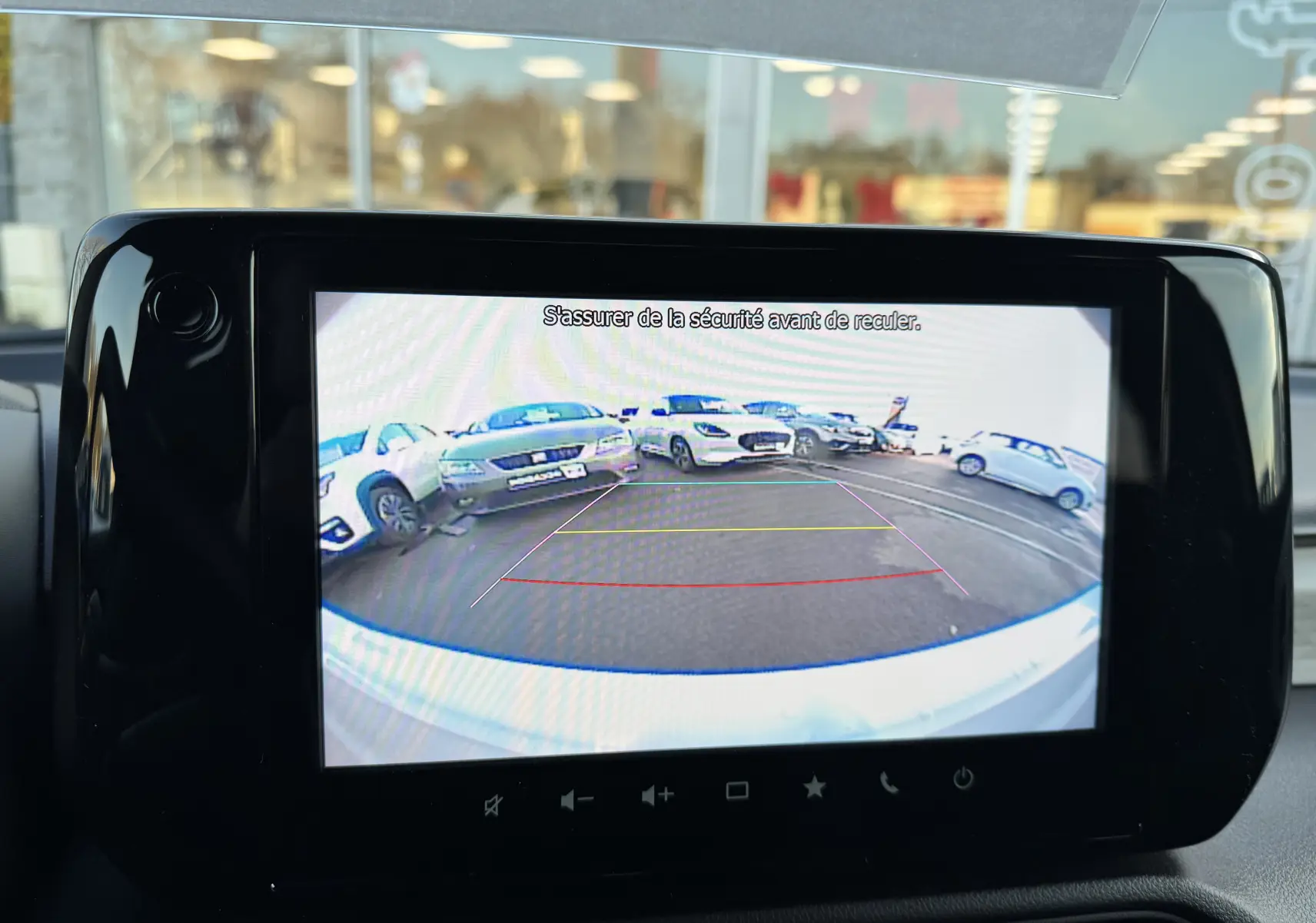 Vue de la caméra de recul de la Suzuki Swift blanche 2025, affichant le parking derrière avec lignes d'aide au stationnement.