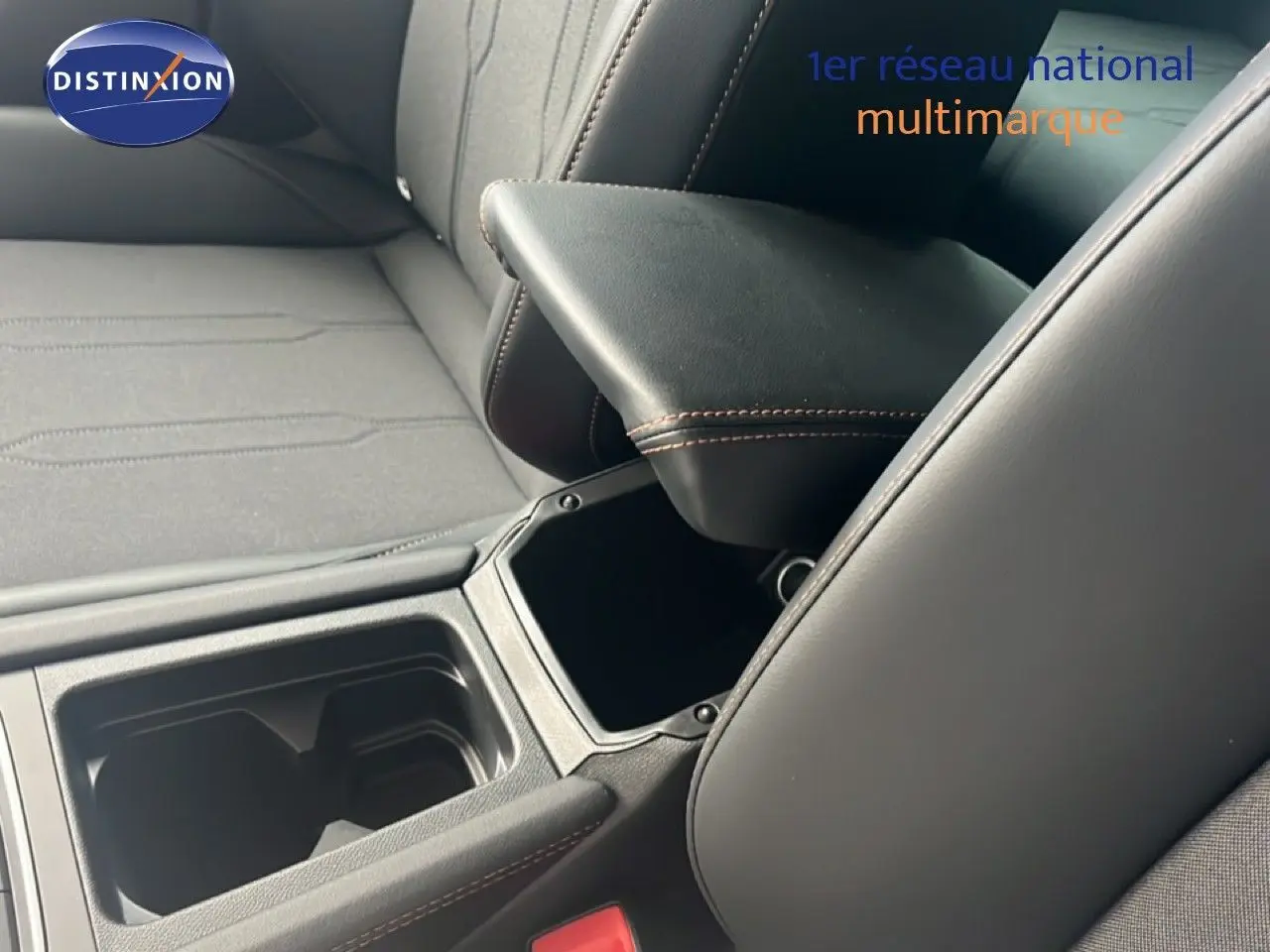 Détail de l’accoudoir central ouvert et des sièges en tissu et cuir noir à surpiqûres marron dans une CUPRA Formentor bleu Fjord.