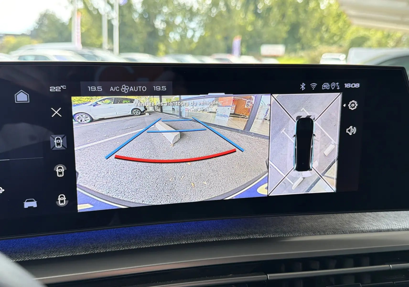 Écran central montrant la caméra de recul et vue 360° du Peugeot 1007 gris Artense en stationnement.