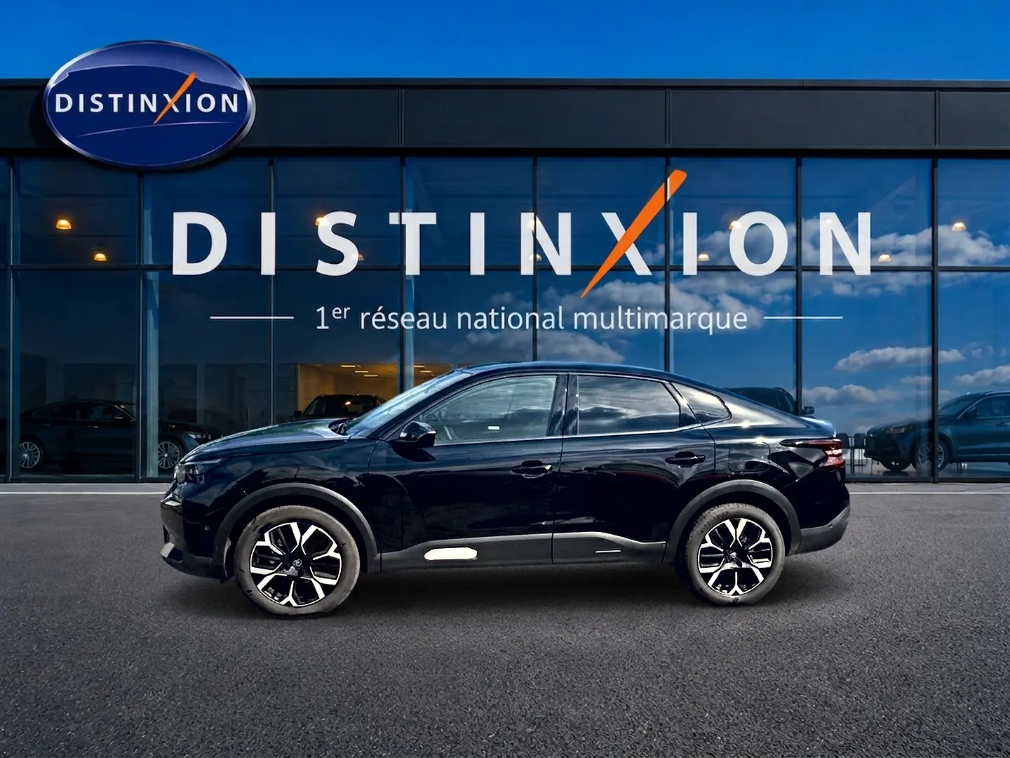 Profil côté gauche d'une Citroën C4 X noire 2025 avec jantes alu et lignes fluides devant une vitrine Distinxion.