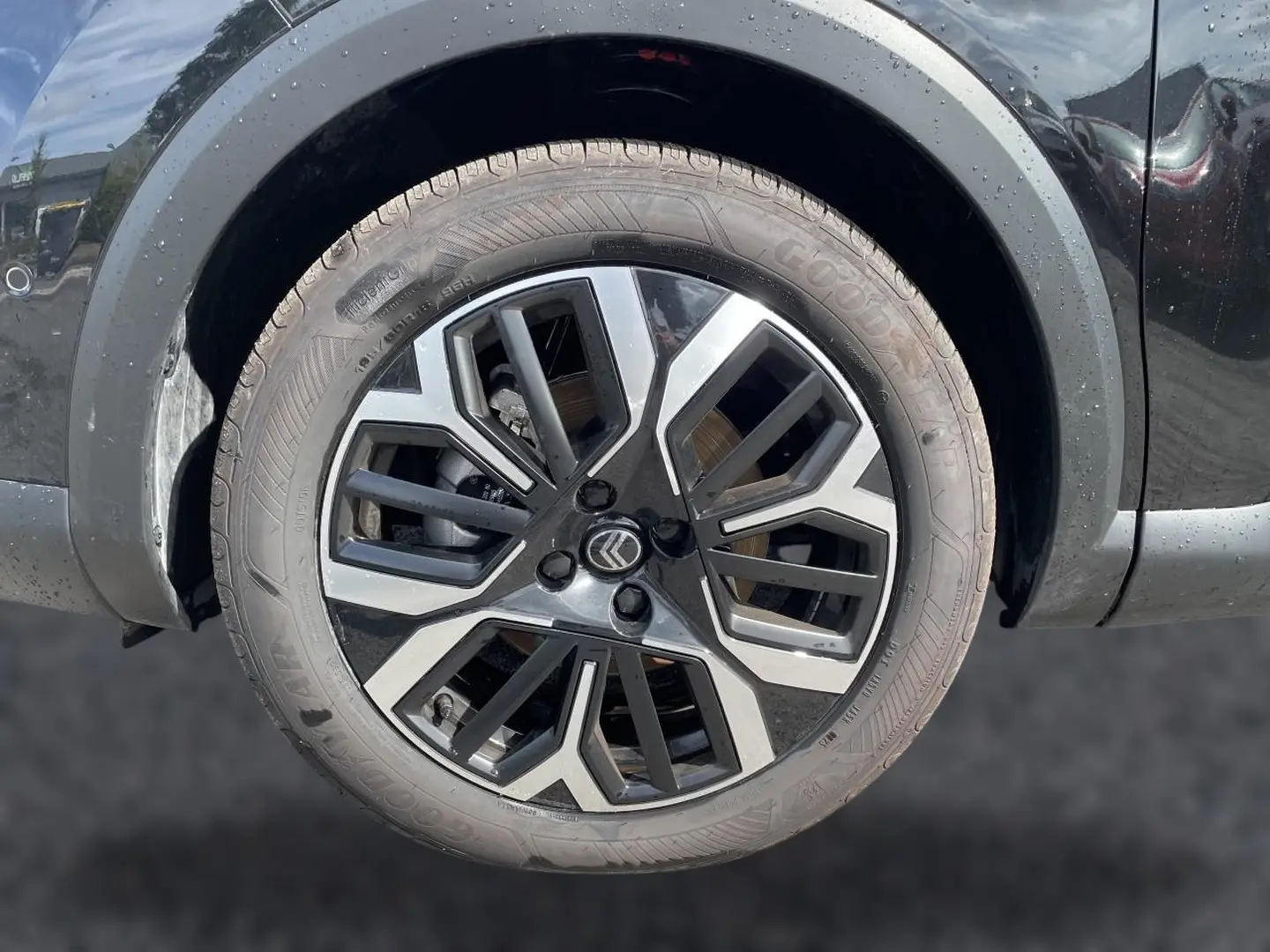 Gros plan sur la jante alu noire et argentée d'une Citroën C4 X noire, avec logo Citroën au centre.