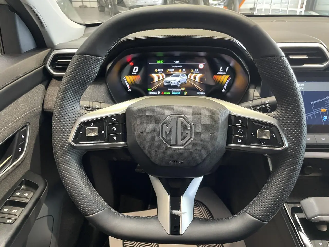 Vue rapprochée du volant en cuir perforé et du tableau de bord numérique du MG Motor ZS 1.5 Hybrid+ gris clair 2026.