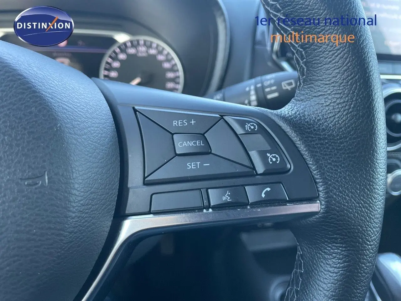 Gros plan sur les commandes au volant en cuir noir du Nissan Juke gris squale métal, version hybride 2024.