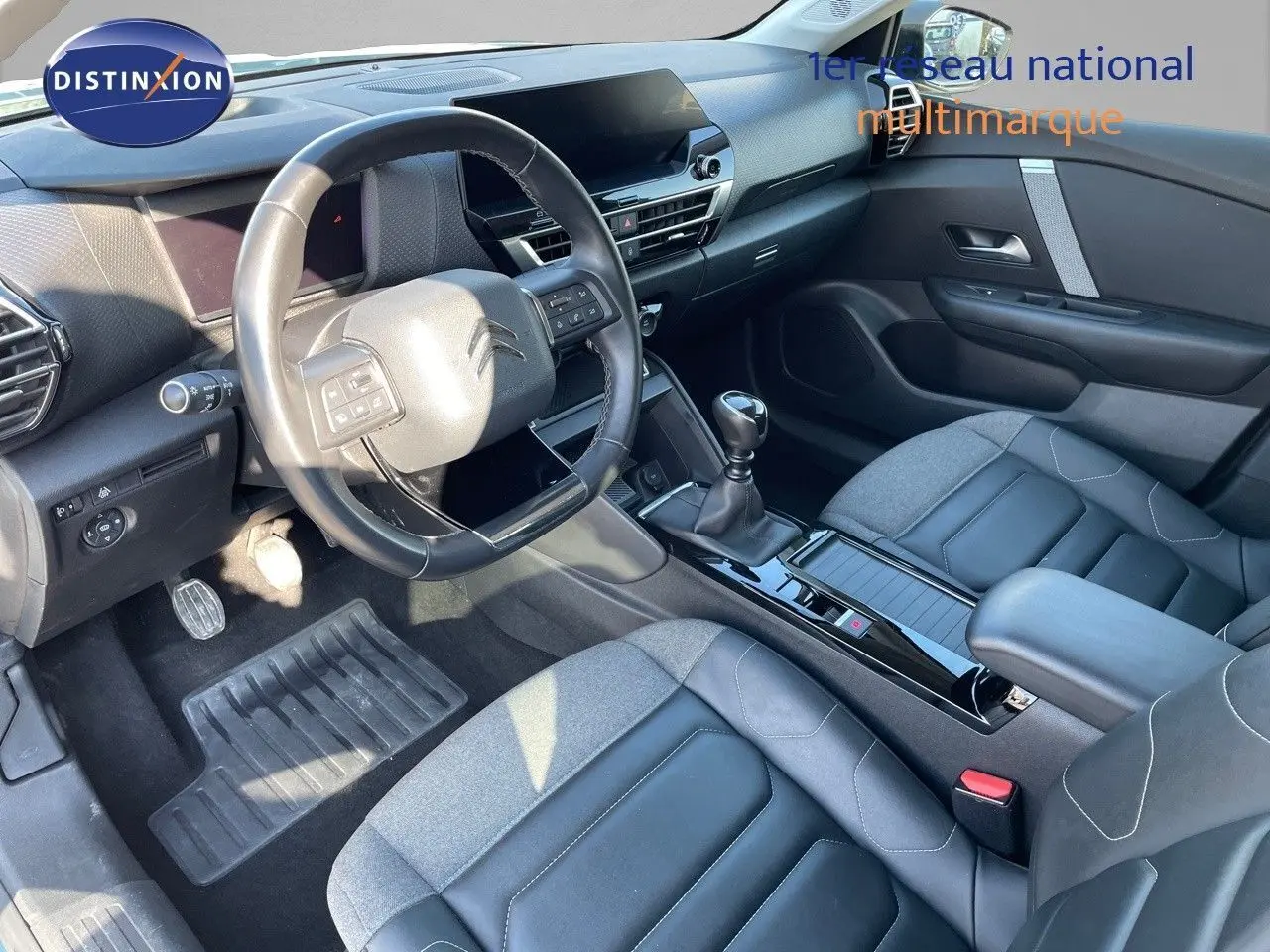 Intérieur de la Citroën C4 2021, vue côté conducteur, sièges bi-matière gris et tableau de bord moderne noir.