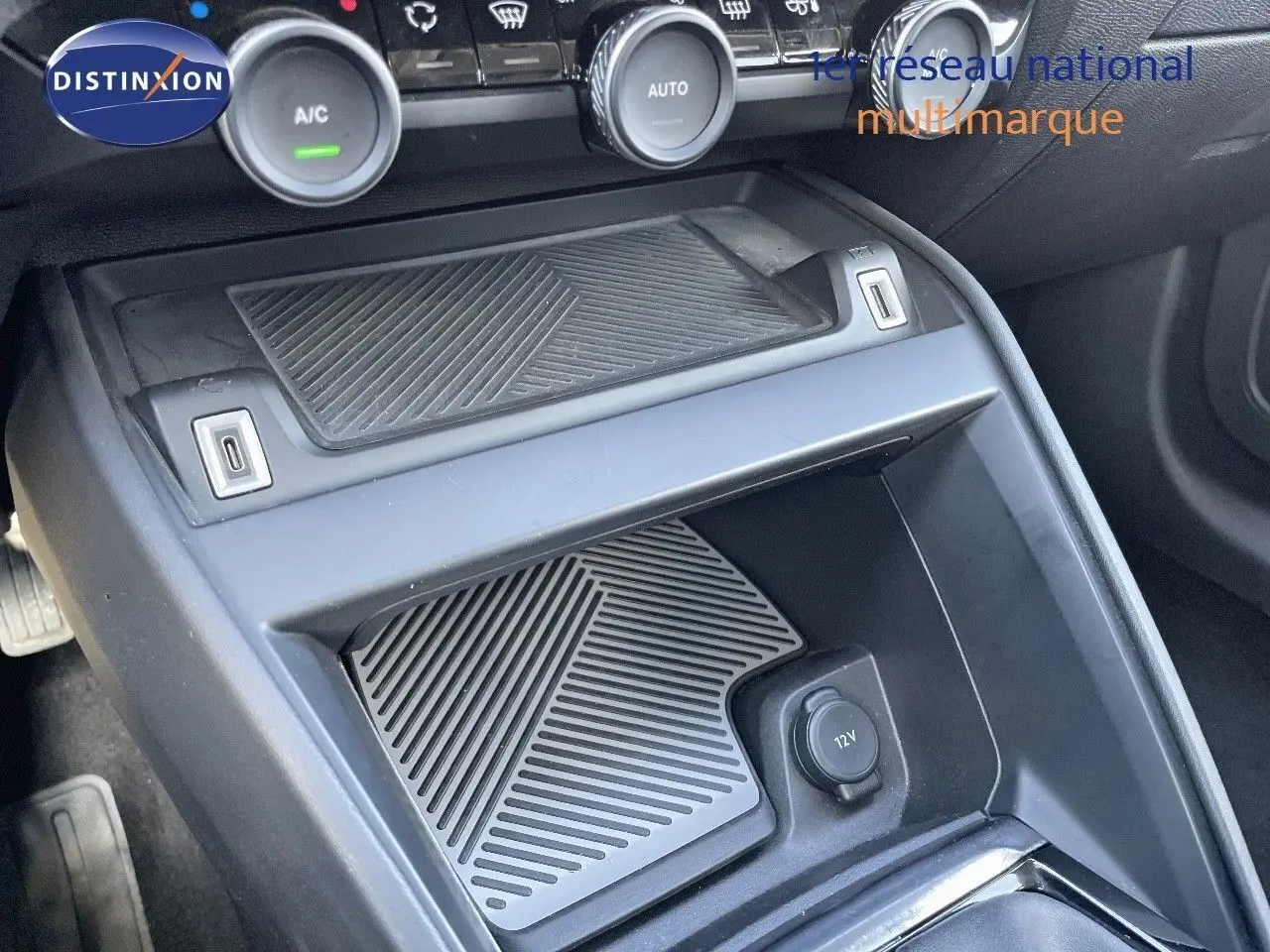 Vue rapprochée de la console centrale noire du Citroën C4 2021 avec commandes climatisation et prise 12V visible.