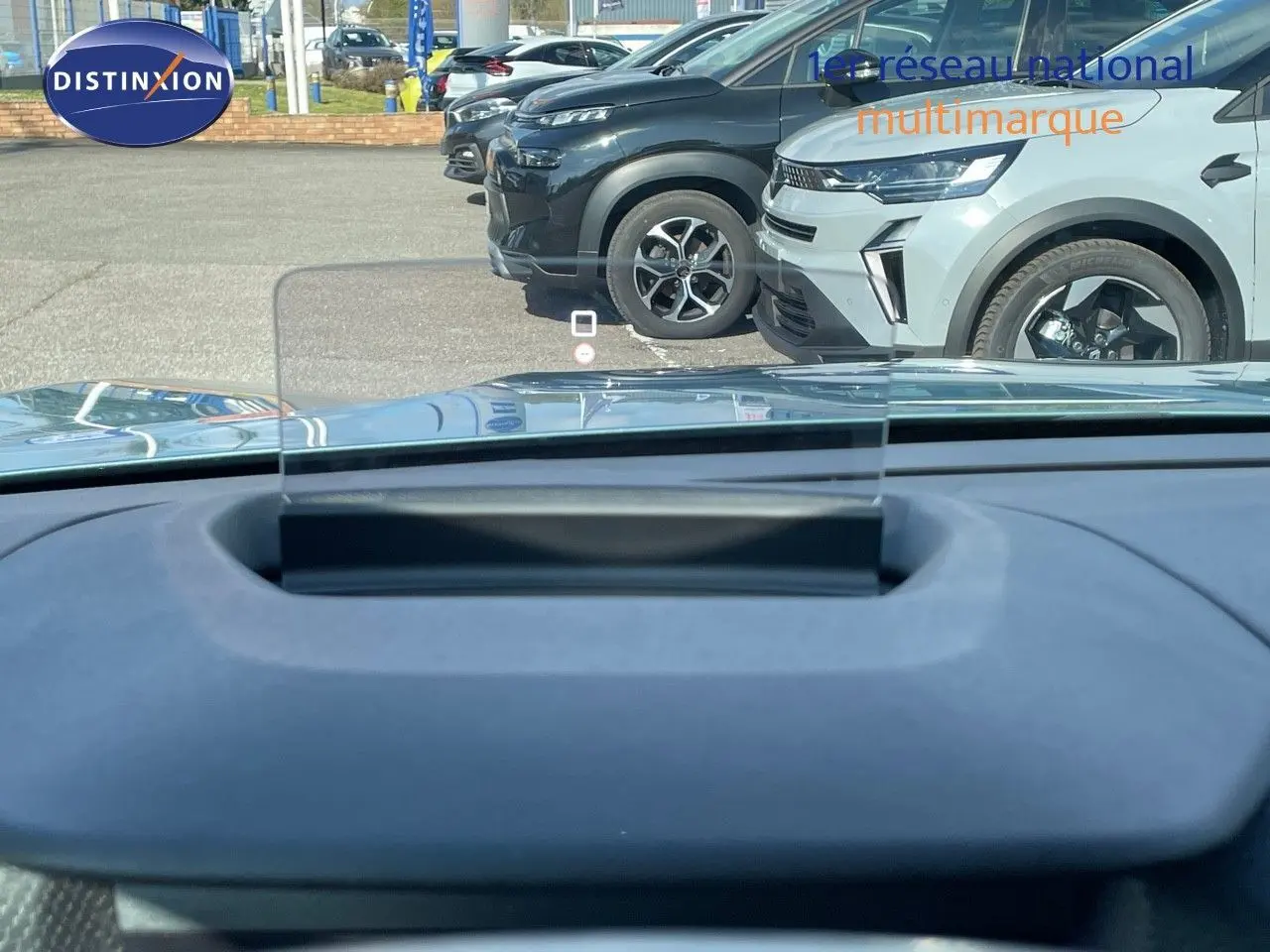 Vue depuis le tableau de bord d'une Citroën C4 bleu Iceland Metal, avec affichage tête haute transparent visible.