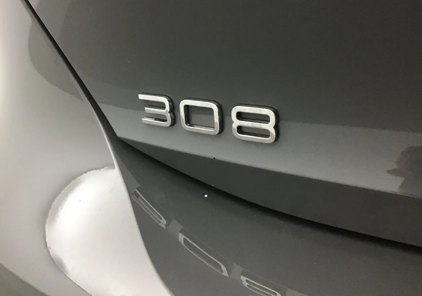 Gros plan sur l'arrière gris selenium du Peugeot 308 avec le badge 308 en relief métallique.