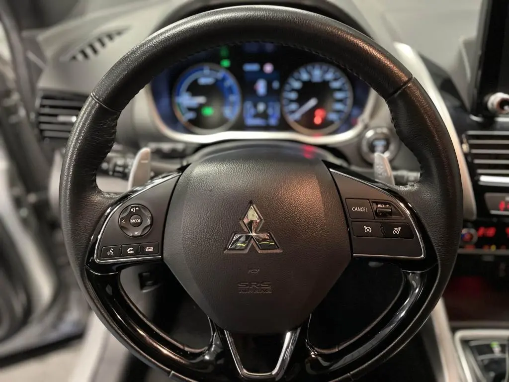 Volant en cuir noir du Mitsubishi Eclipse Cross 2022 avec commandes multifonctions et tableau de bord lumineux en arrière-plan.