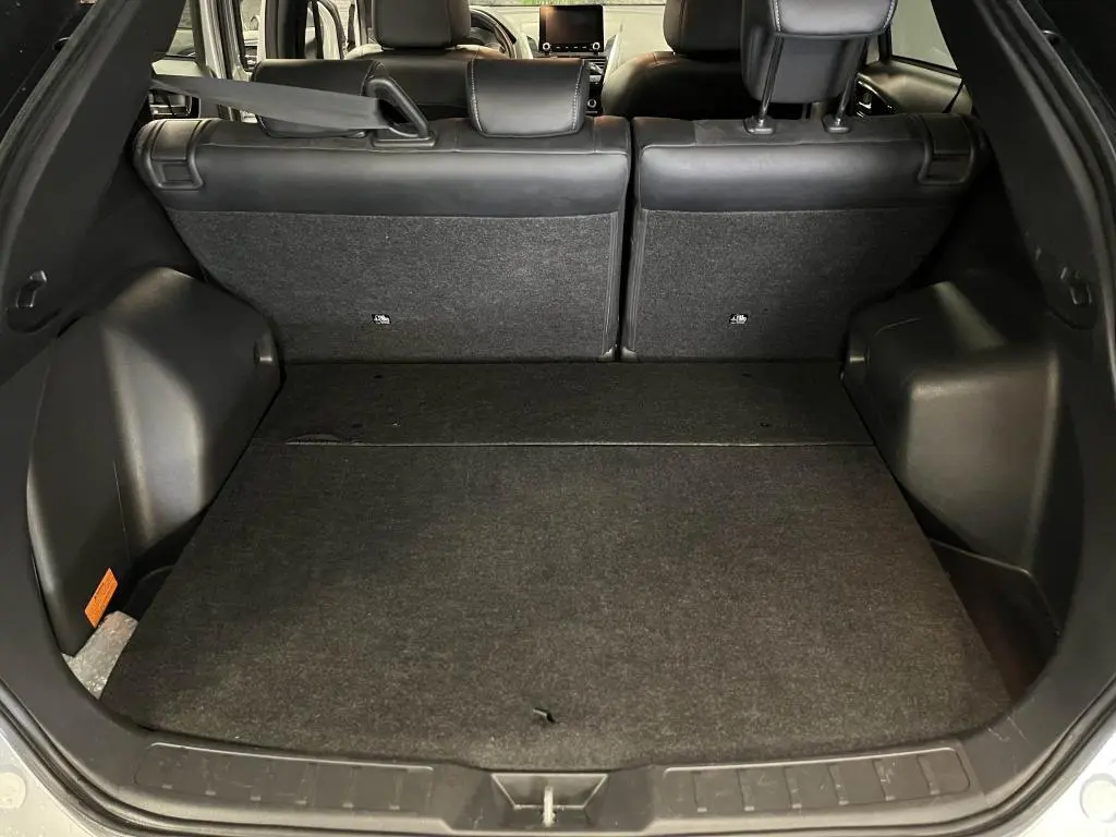 Coffre ouvert du Mitsubishi Eclipse Cross gris, vue arrière montrant banquette arrière et espace de chargement noir.