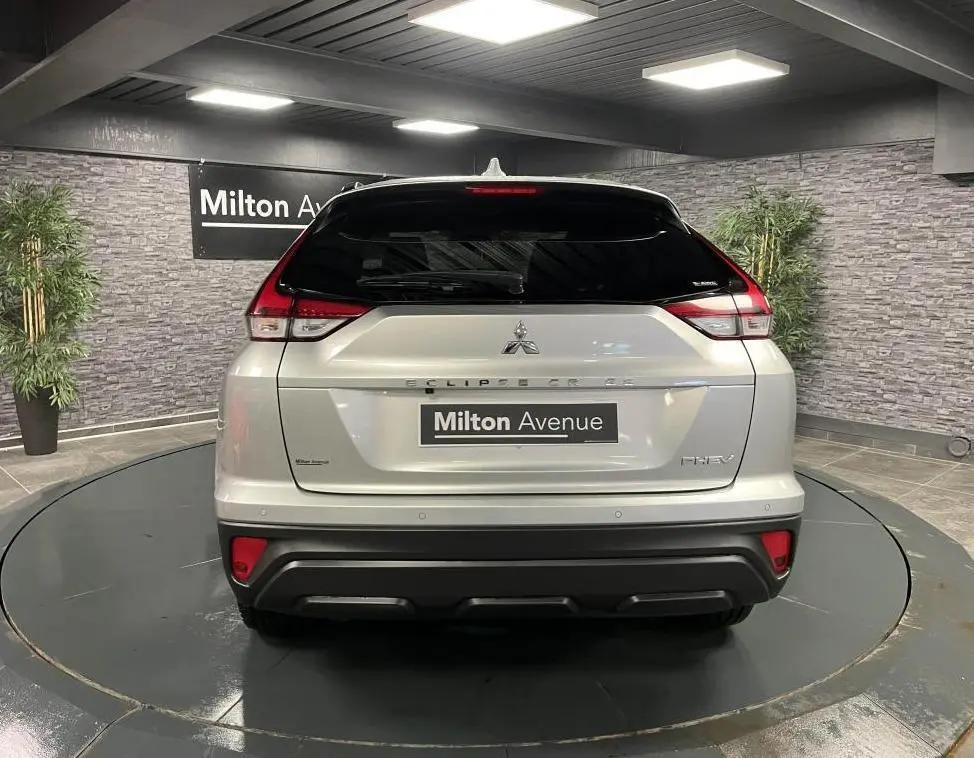 Vue arrière du Mitsubishi Eclipse Cross gris métallisé avec feux arrière LED et logo PHEV visible en intérieur showroom.