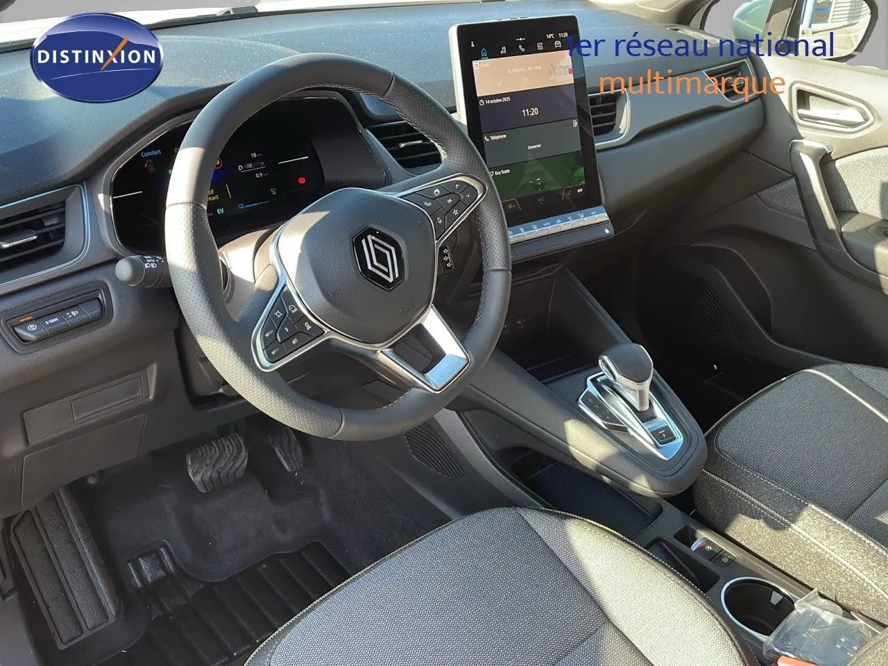 Intérieur du Renault Captur E-Tech hybride 2025, vue du poste de conduite avec volant multifonction et écran tactile vertical.