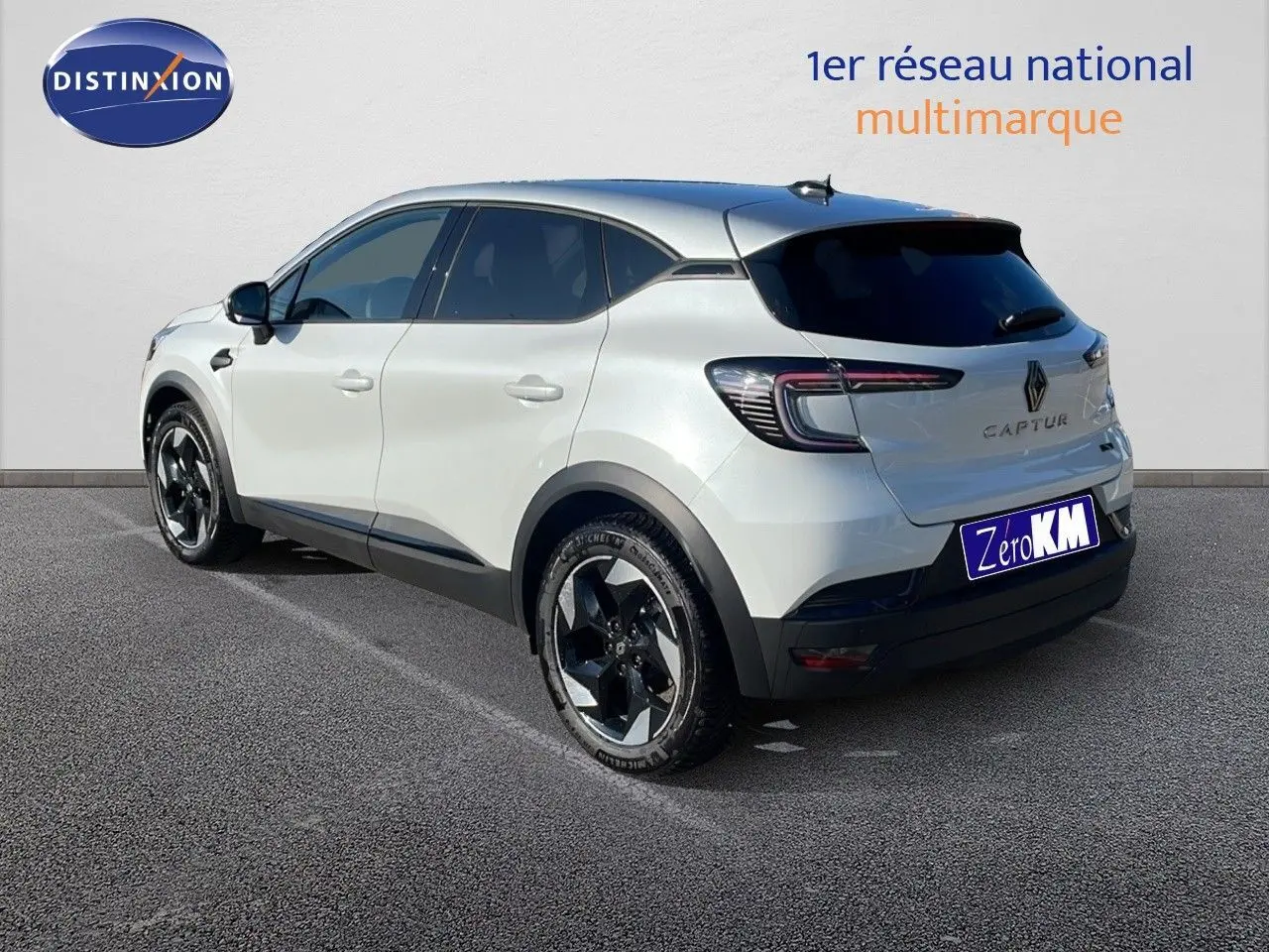 Vue 3/4 arrière gauche d'un Renault Captur blanc nacré avec toit gris et jantes noires distinctives.