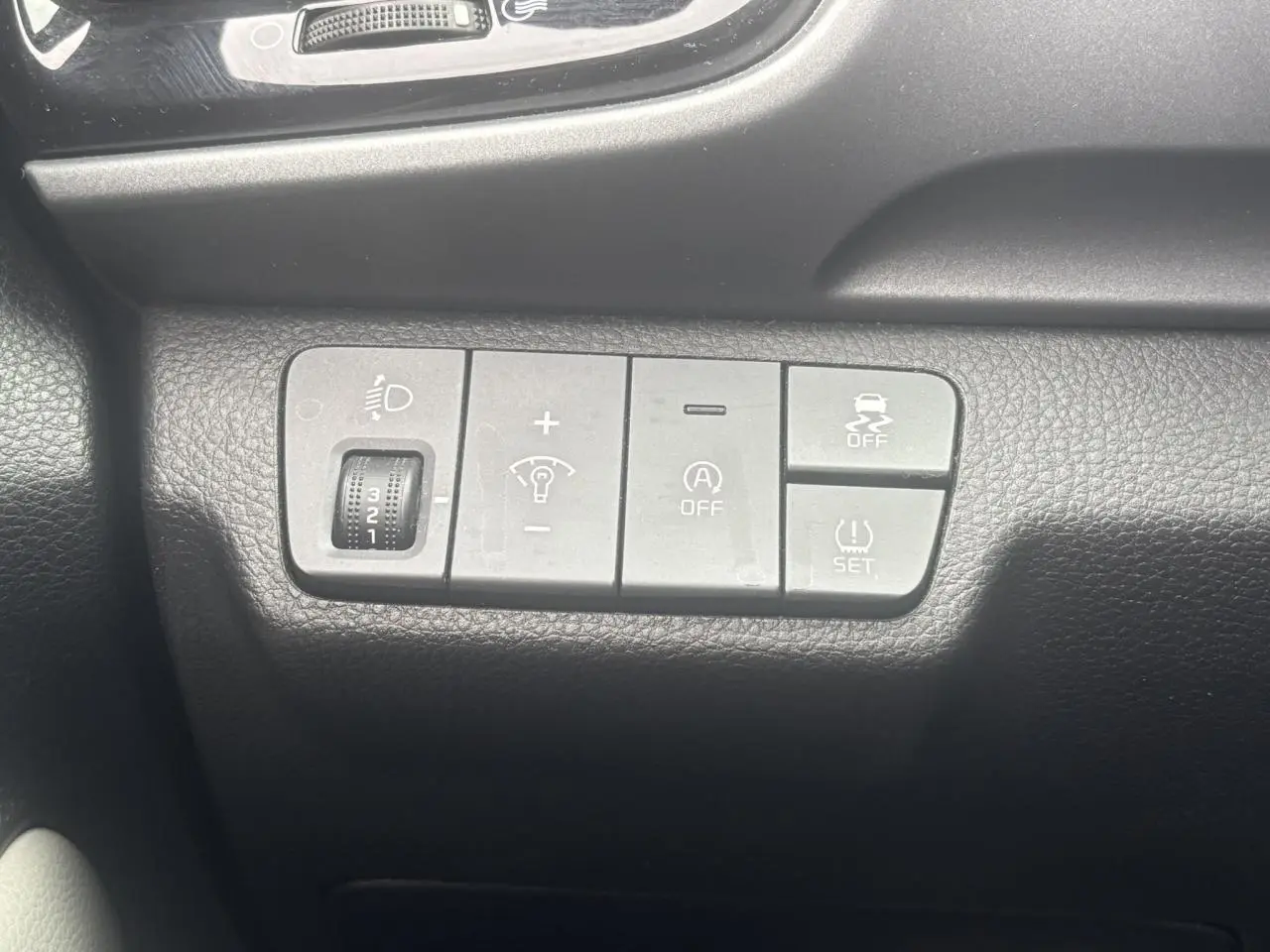 Gros plan sur les commandes de réglage d’éclairage et d’assistance du tableau de bord du Kia Stonic rouge 2020.