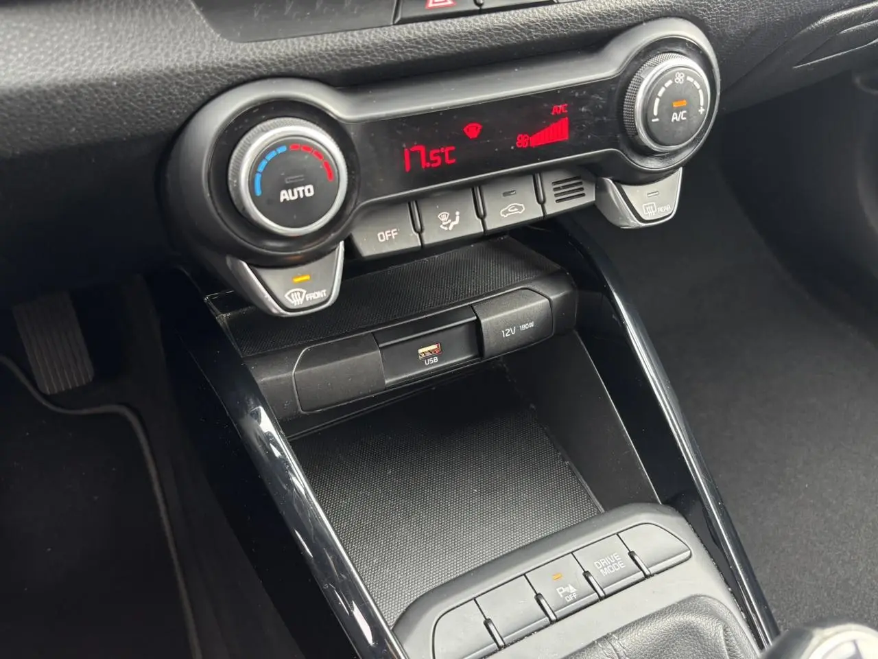 Vue rapprochée de la console centrale noire du Kia Stonic rouge, avec commandes climatisation et ports USB visibles.