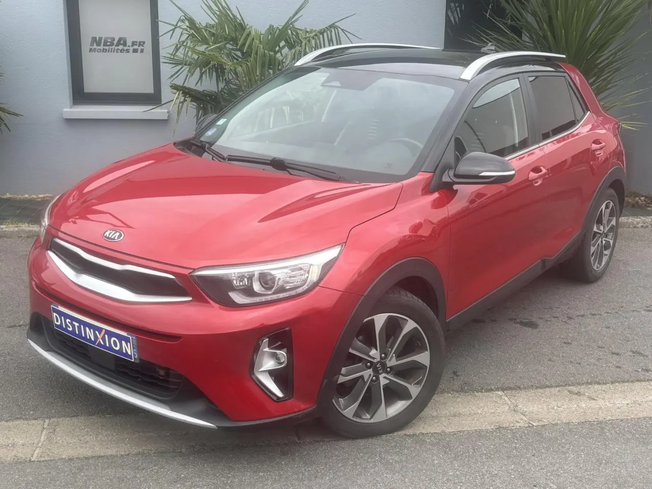 KIA Stonic rouge métallisé vue 3/4 avant droit avec toit noir et jantes alliage 17 pouces.