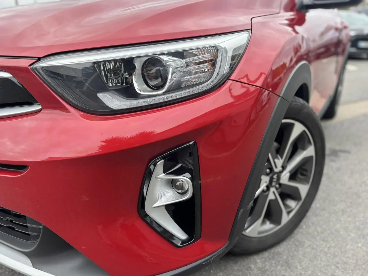 Gros plan sur l'avant droit rouge métallisé du KIA STONIC 2020, mettant en valeur le phare et le projecteur antibrouillard.