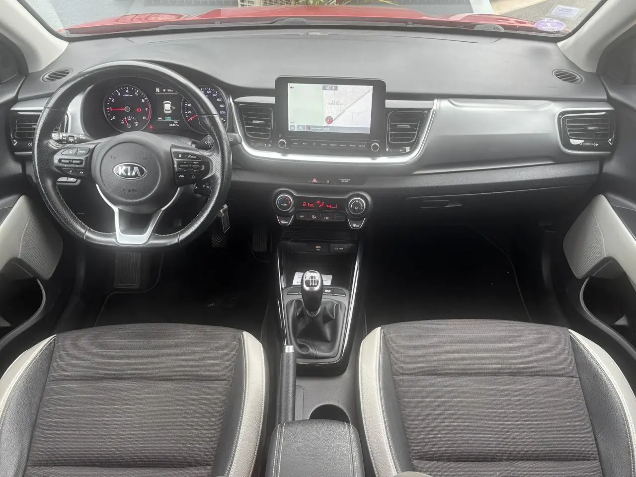 Vue intérieure frontale du tableau de bord et volant KIA Stonic avec écran tactile et boîte manuelle.