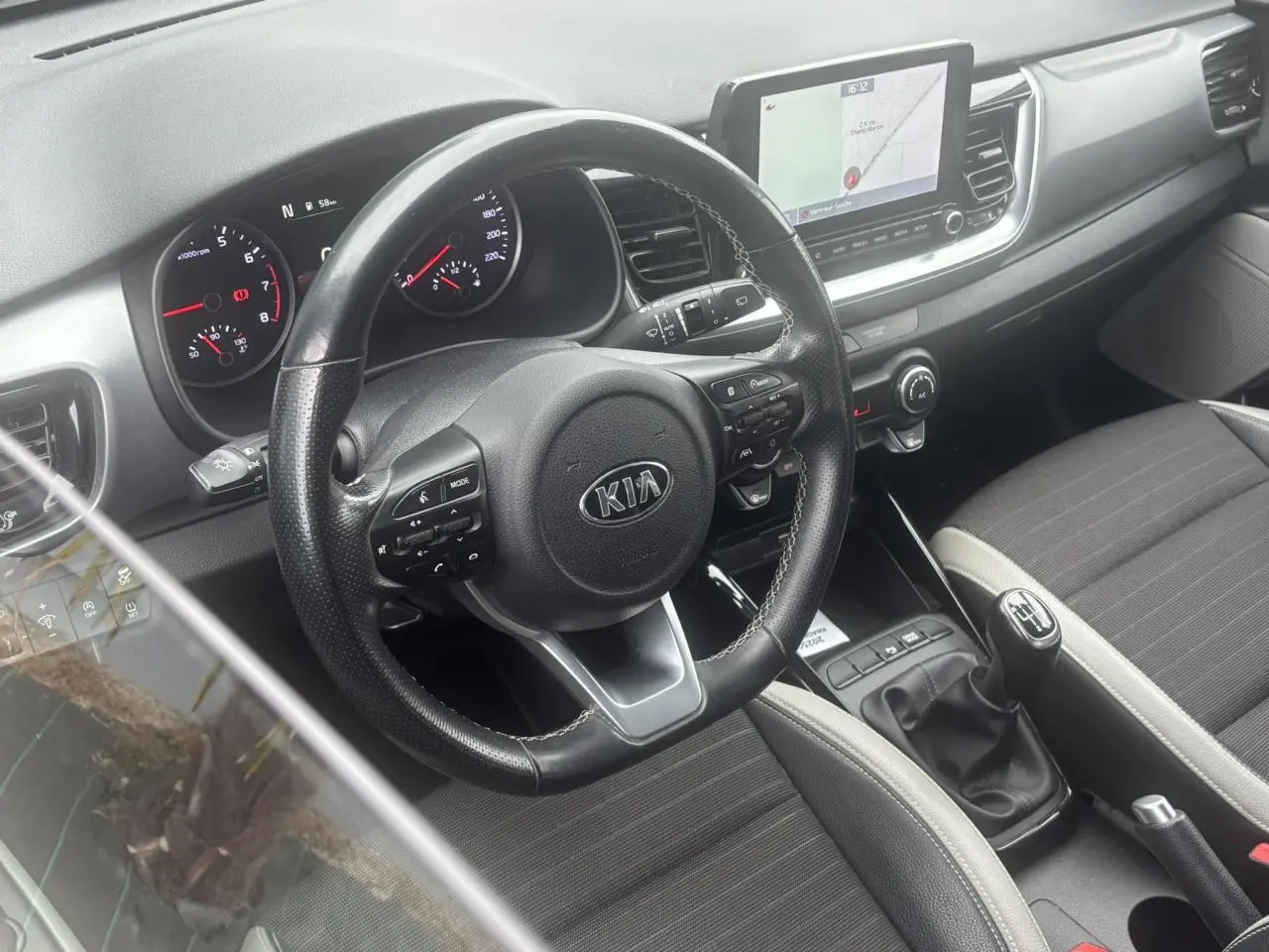 Vue intérieure côté conducteur du tableau de bord et volant KIA Stonic avec écran tactile et levier de vitesses manuel.